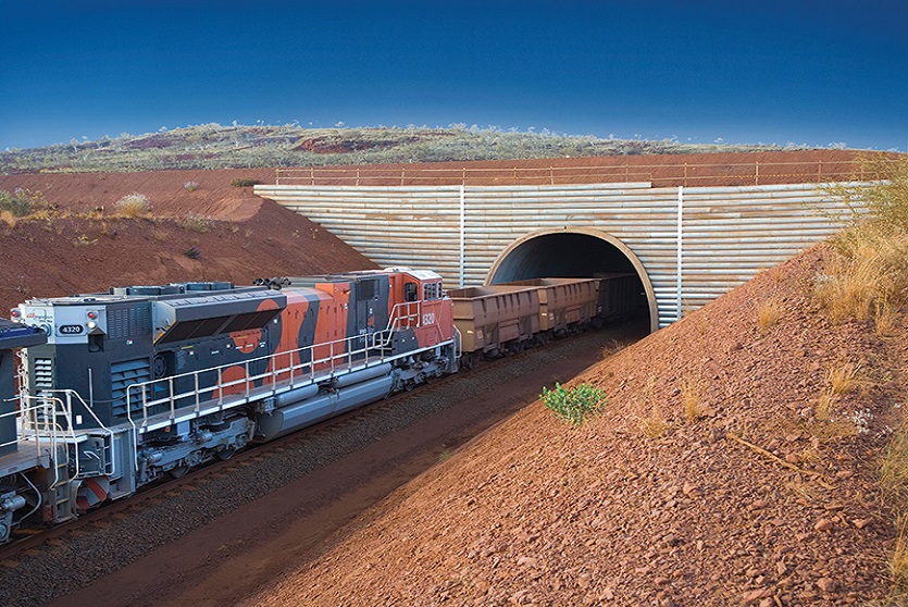 Precast concrete arch solution, TechSpan® by Reinforced Earth pictured at an iron-ore mine, used as a railway tunnel with a train seen entering the precast concrete arch structure